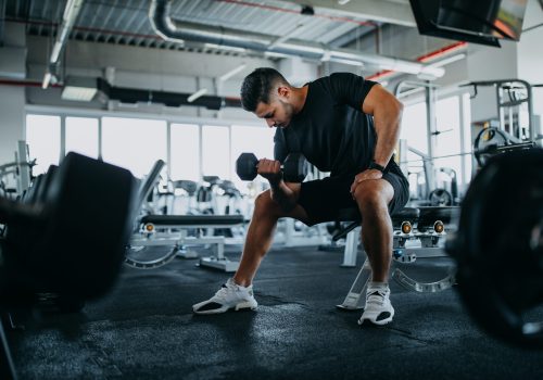 At gym, sitting and holding weight.