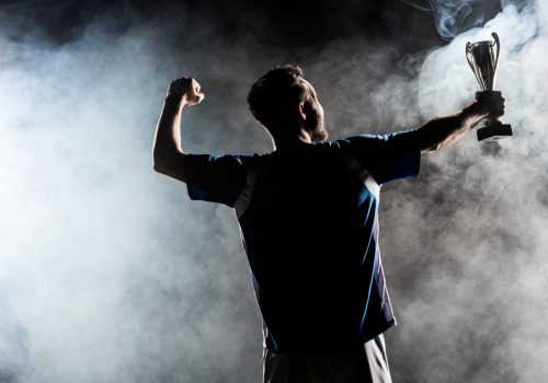 silhouette of man standing with trophy on black with smoke