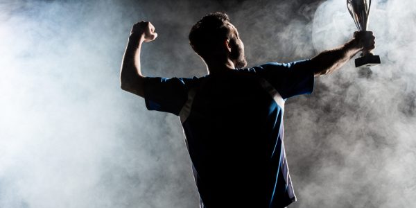 silhouette of man standing with trophy on black with smoke